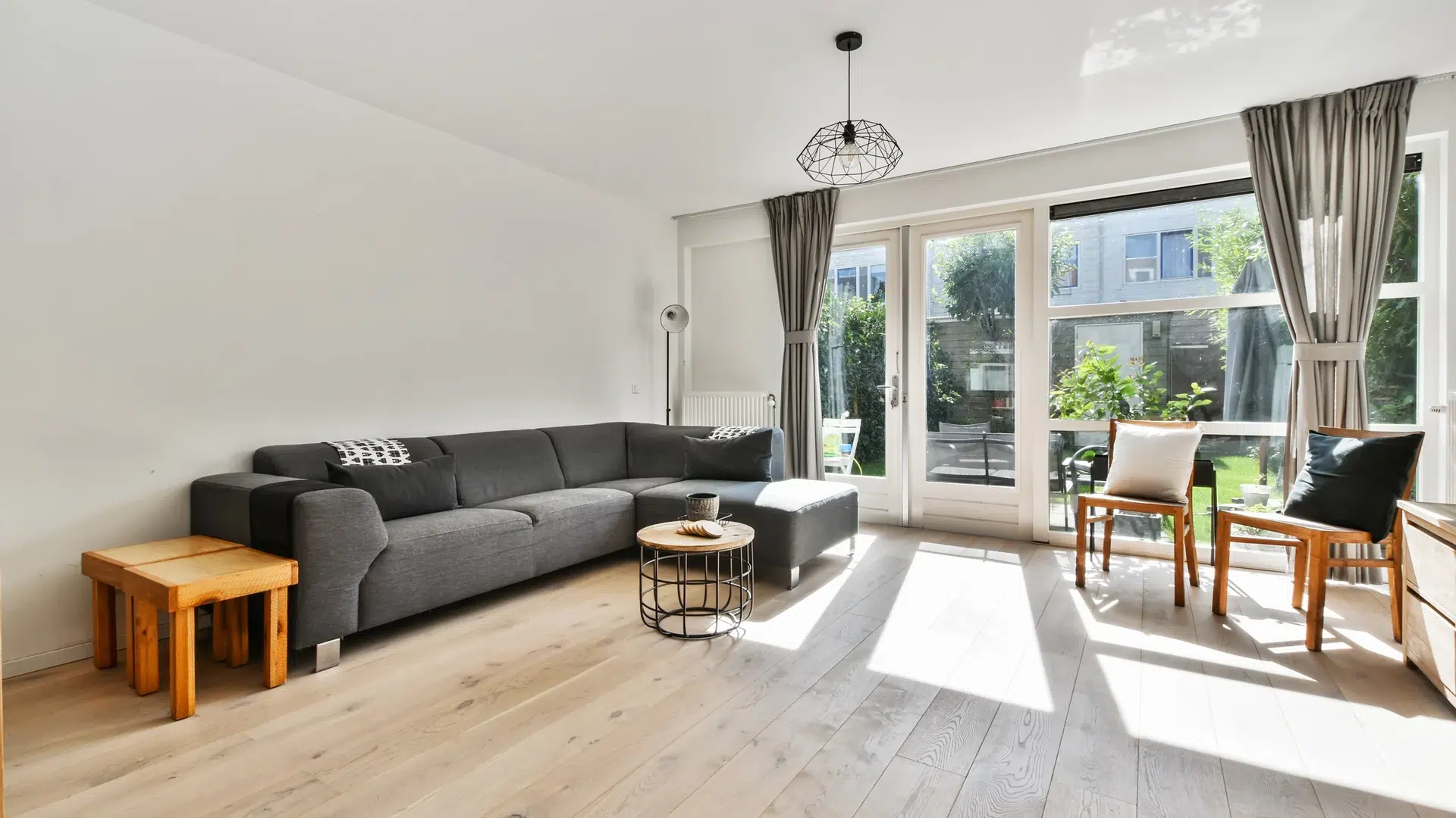 Salon moderne avec canapé gris et grandes fenêtres