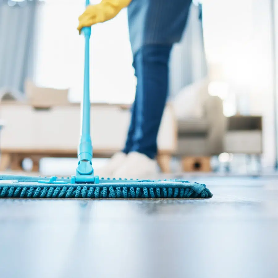 Personne nettoyant le sol avec une serpillière bleue